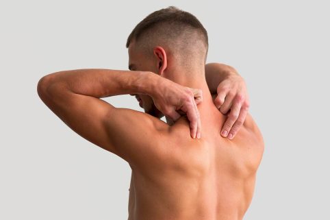 Mann greift mit einer Hand hinter seinen Rücken, zeigt verspannten Nacken.