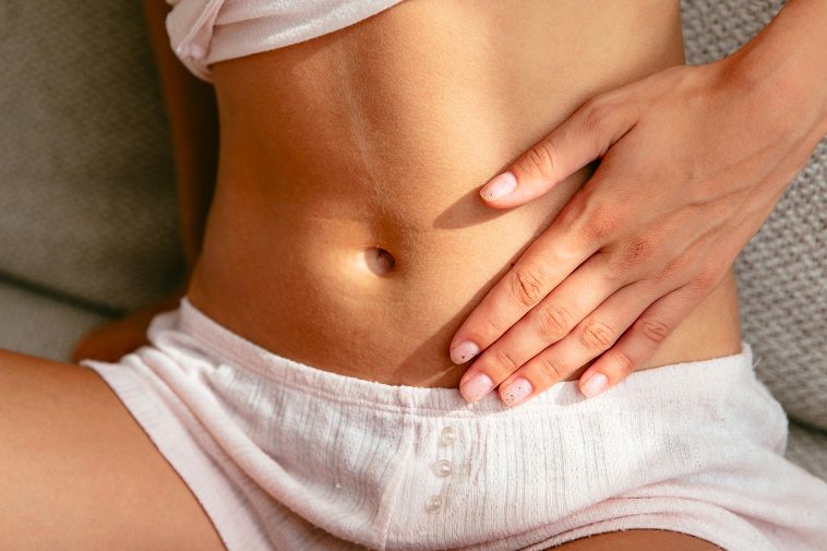 Eine Frau sitzt mit einer Hand auf dem Bauch.