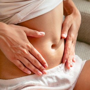 Eine Frau hält sich den Bauch.