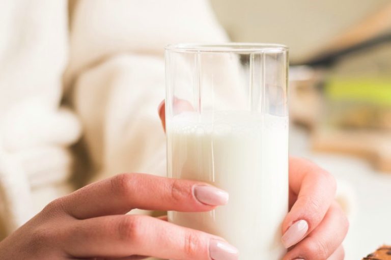 Hände halten ein Glas Milch.