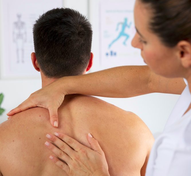 Heilpraktikerin behandelt den Rücken eines Patienten in der Heilpraxis.